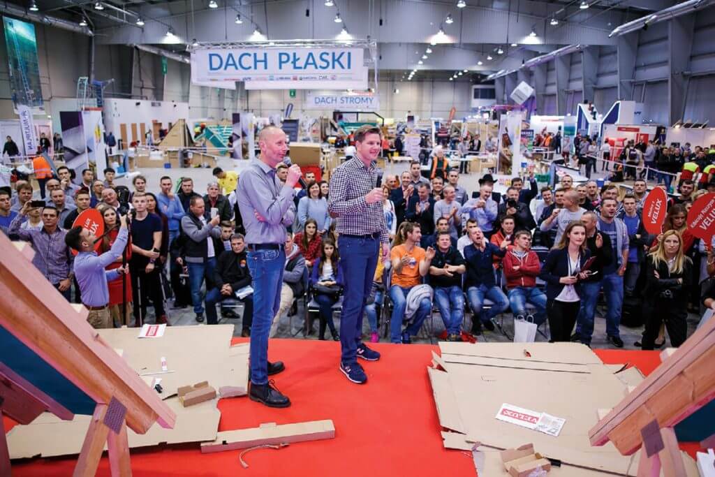 Filip Chajzer i doradca techniczny VELUX, Jarosław Grzech dopingują drużyny, które walczyły o ustanowienie Rekordu Polski w montażu okna dachowego VELUX na czas.