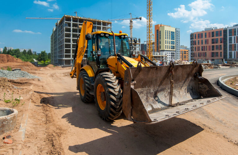 zolty-traktor-na-placu-budowy-ustawia-slupy-w-terenie